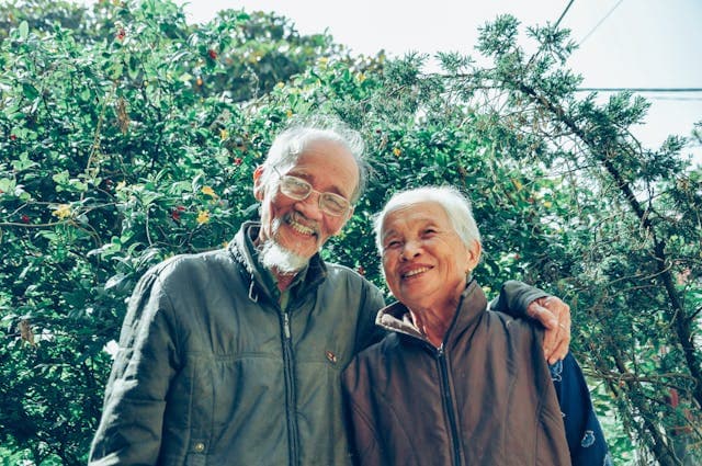 older man and woman stood outside smiling with arm around each other