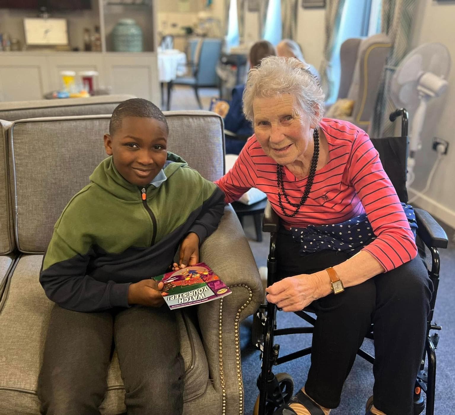 resident having a book read to her by a schoolboy