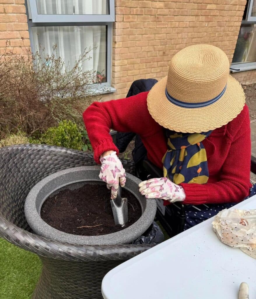 resident with straw hat on planting in a pot