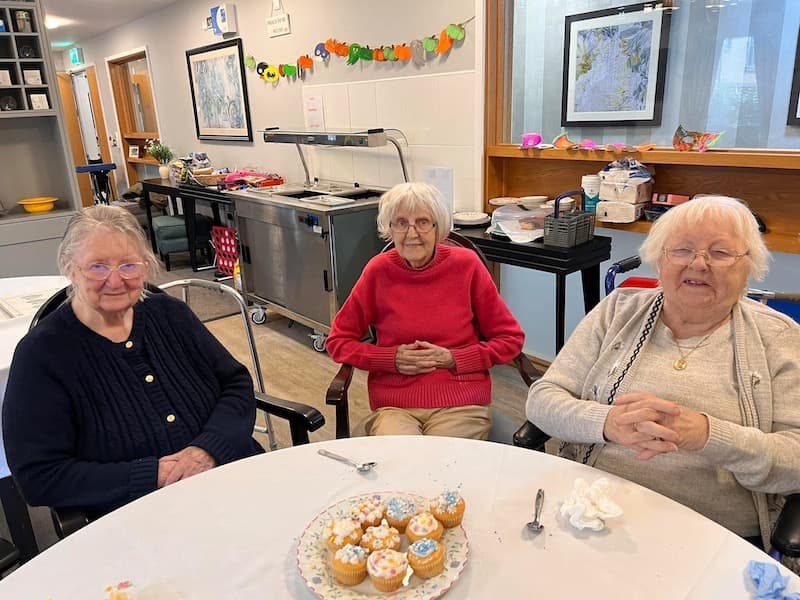 residents sat down together smiling after decorating cupcakes