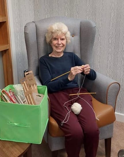 A resident knitting a blanket at Ty Llandaff Care Home