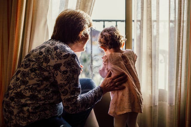 resident next to her younger grandchild looking out the window
