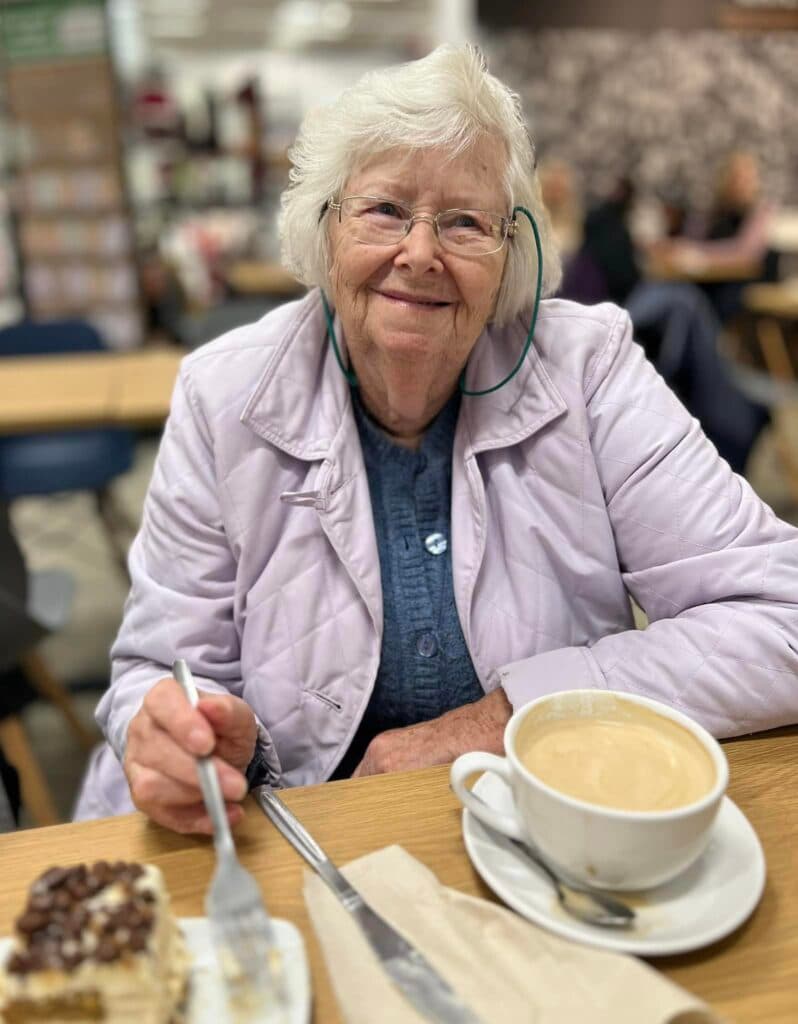 resident smiling with a coffee and donut