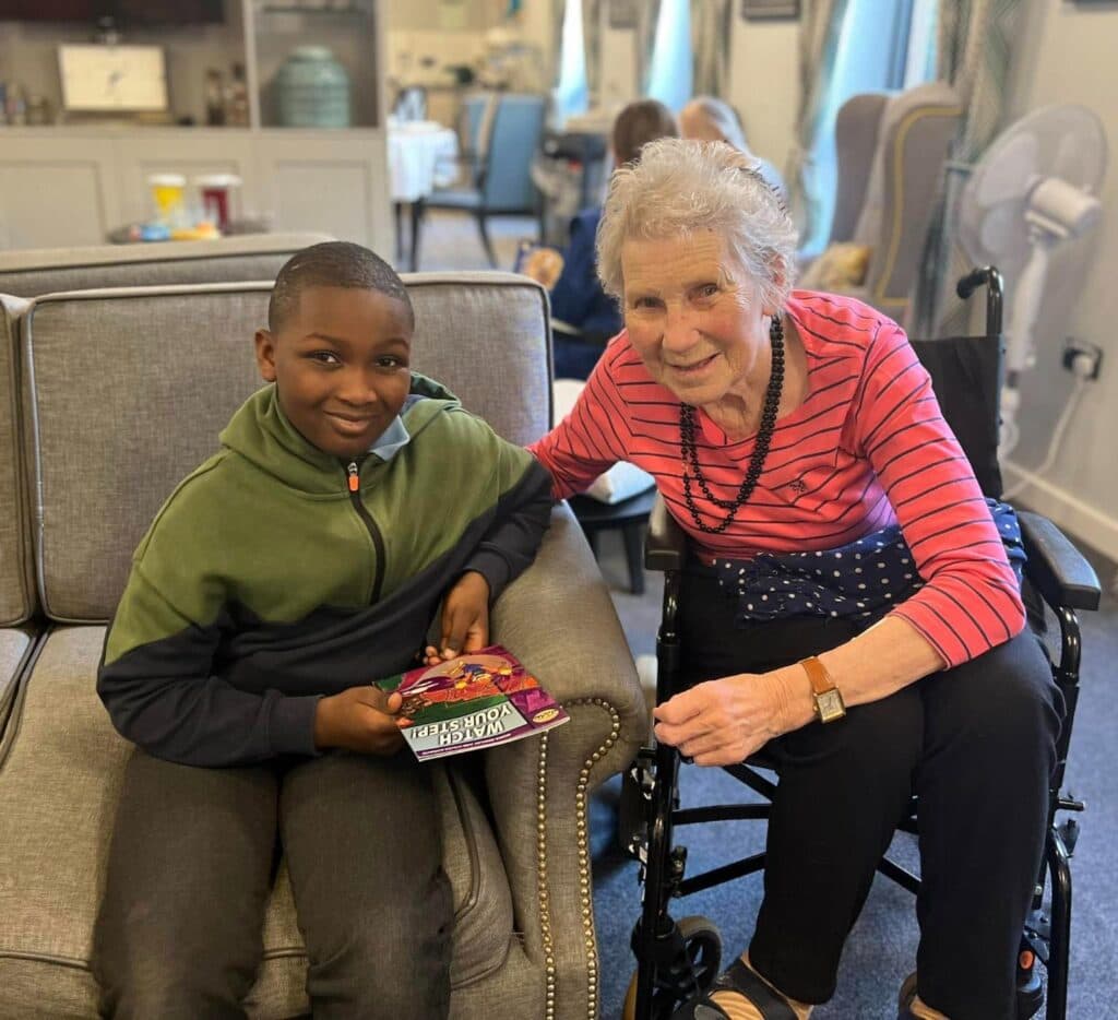 resident having a book read to her by a schoolboy