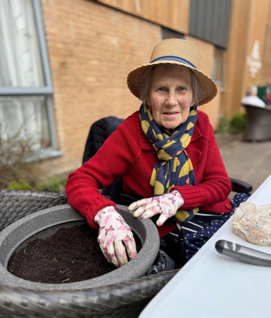 resident with straw hat on planting in a pot