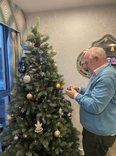 Resident adding bauble onto Christmas tree