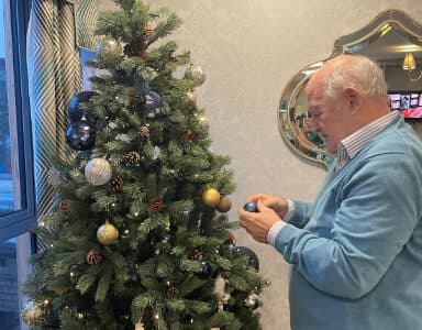 Resident adding bauble onto Christmas tree