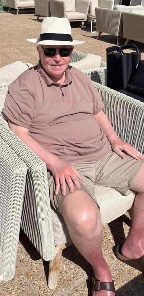 resident wearing a pink top and a hat sat in a chair smiling