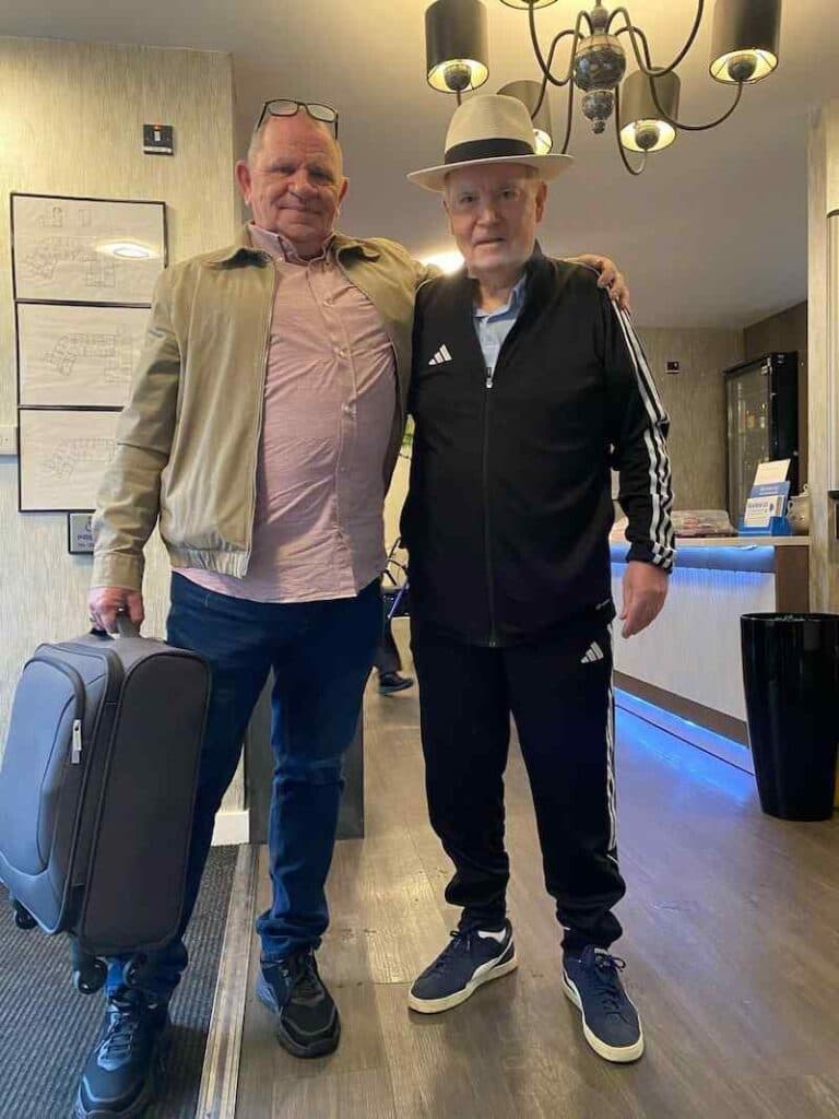 resident stood with carer smiling with a suitcase in his hand